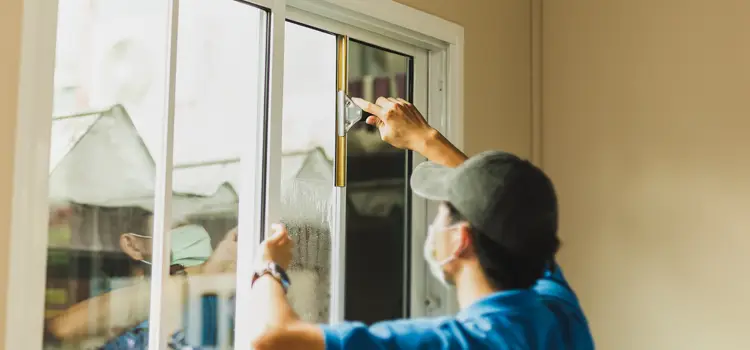 worker putting on window film in a home