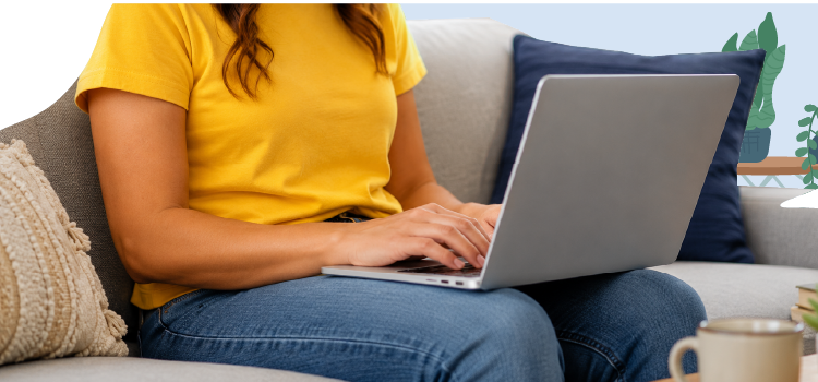 A person sitting on a sofa wearing a yellow shirt and blue jeans while working on a laptop. A-person-sitting-on-a-sofa-wearing-a-yellow-shirt-and-blue-jeans-while-working-on-a-laptop